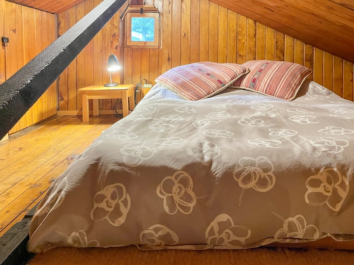 Loft vo veľkej cabane. Priestor s nízkym stropom s dvojitým matracom na drevenom bunkri.