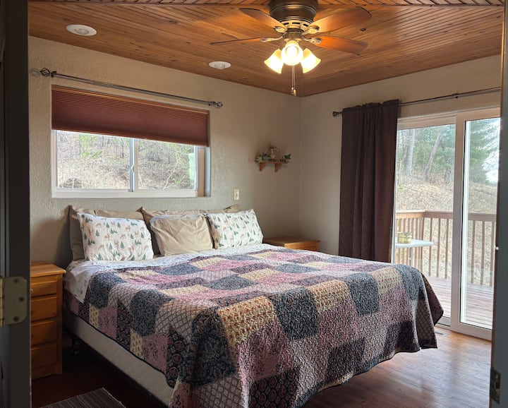 King Bedroom with hand made dressers on each side of the bed, separately switched reading lights above the bed ceiling fan, and a ceiling Larry made from reclaimed wood. Patio doors to the balcony on the right.