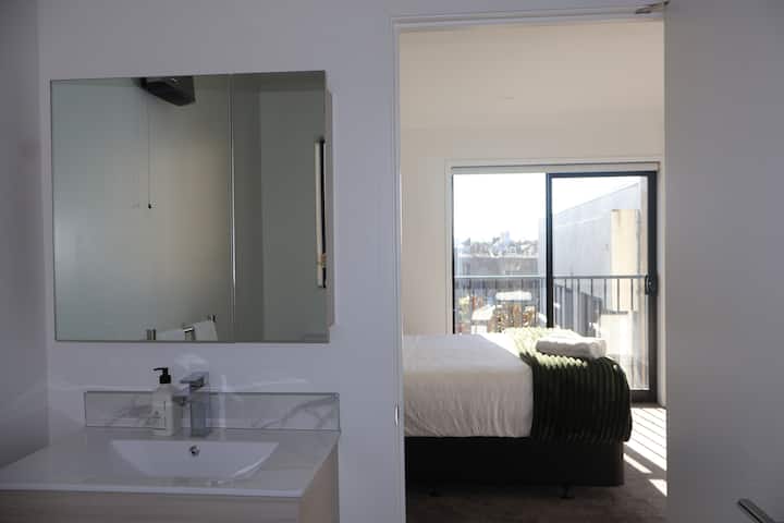 Nuestro amplio dormitorio tiene un baño privado. Disfruta de acceso a una moderna ducha, inodoro y tocador. Nuestro espacioso tocador tiene un gran espejo y un amplio espacio de almacenamiento debajo del lavabo.