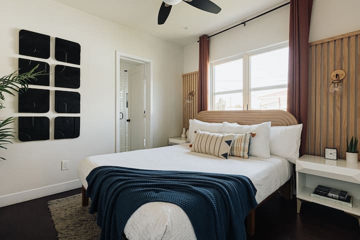 ห้องนอนหลักมีที่พักผ่อนที่เงียบสงบพร้อมเตียงควีนไซส์ที่อบอุ่น การตกแต่งด้วยไม้ที่อบอุ่น และการตกแต่งที่ทันสมัย หน้าต่างบานใหญ่ช่วยให้แสงธรรมชาติเข้ามาในที่พัก ส่วนผ้าปูที่นอนเนื้อนุ่ม งานศิลปะที่โดดเด่น และห้องน้ำในตัวก็ช่วยสร้างความสะดวกสบายและมีสไตล์