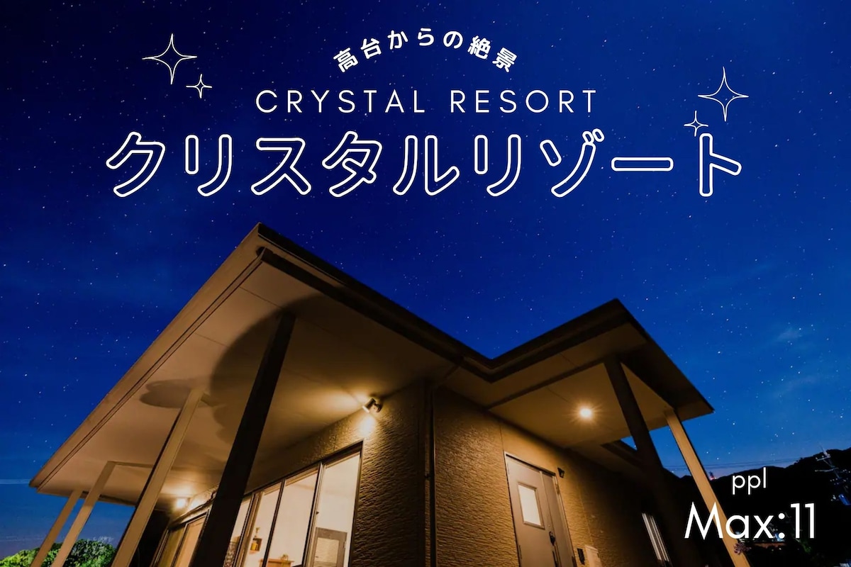 The exterior of a resort is displayed under a night sky filled with stars. The building features modern architecture, including a sloped roof and warm exterior lighting, creating a tranquil ambiance.