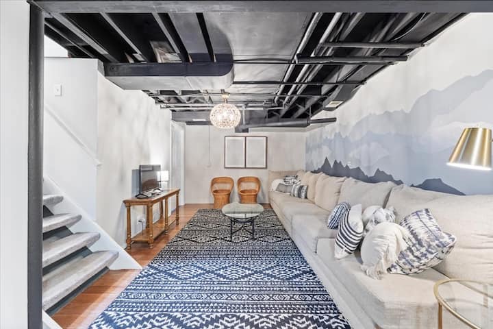 Den ekstra, ekstra lange sofa er perfekt til filmaften. Indgangen til et vaskerum er til venstre for stolene, og trapper fører til hovedhuset ovenpå.