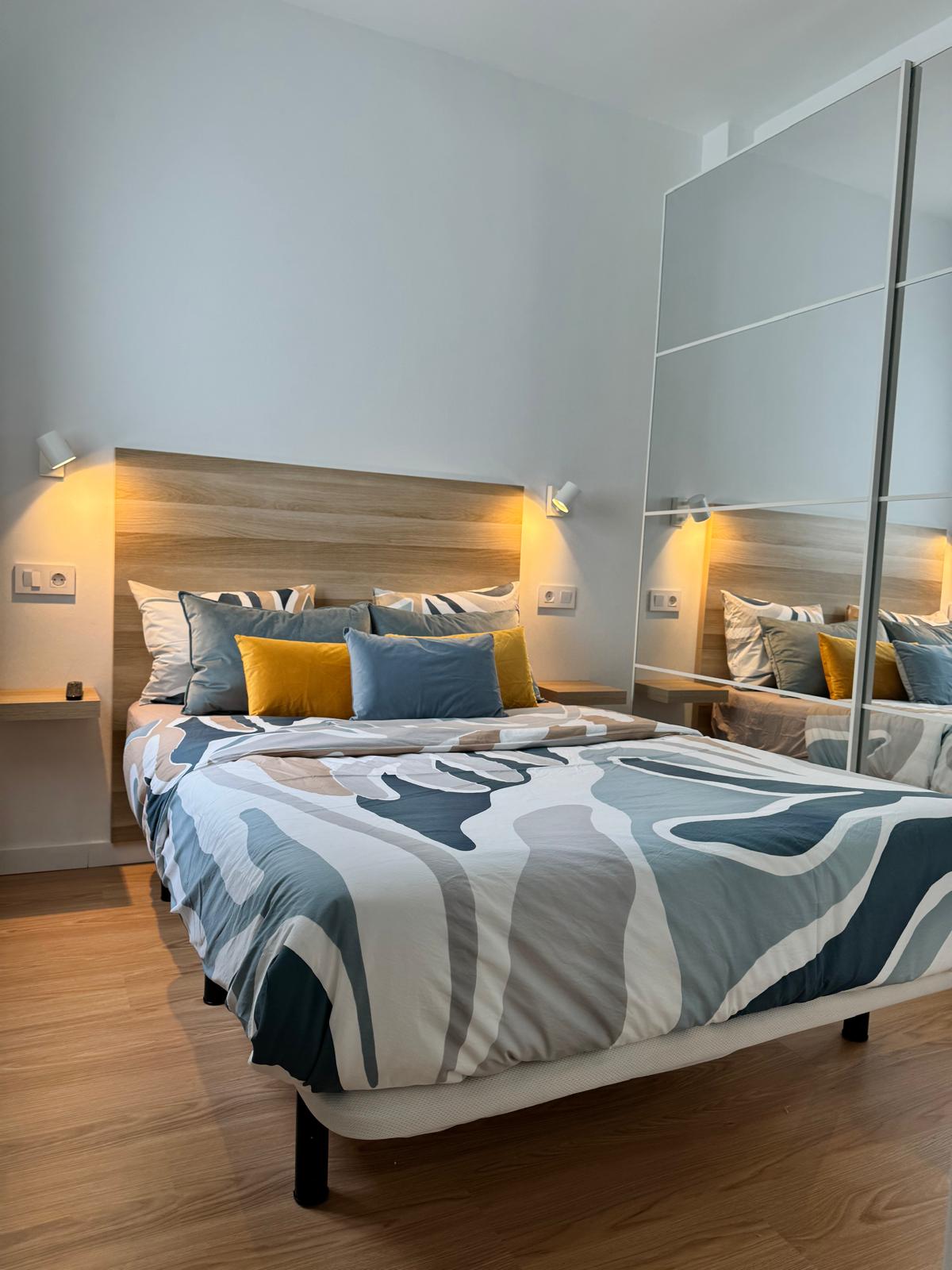 غرفة نوم مزدوجة مريحة مع إضاءة ناعمة وخزانة ملابس مدمجة وفراش مريح بألوان هادئة.