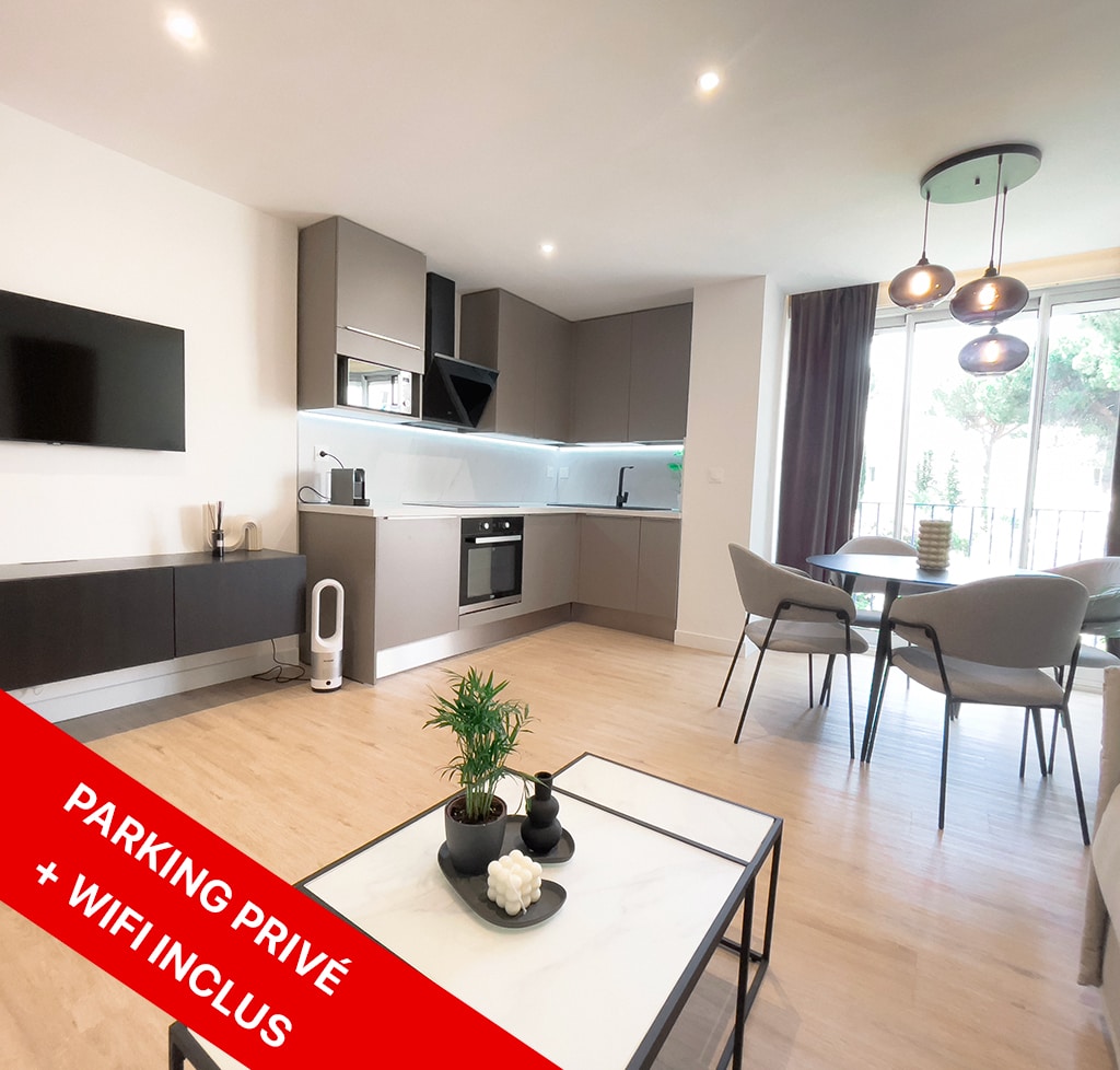 The modern kitchen is equipped with contemporary appliances, including an oven and a refrigerator. A stylish dining area features a round table surrounded by four chairs. Natural light fills the space through large windows, with a scenic view of the garden visible outside.