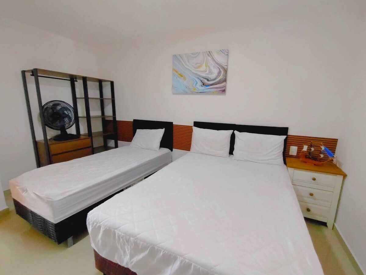 Спална соба 1, опремена со двоен кревет и единечен кревет, преносни вентилатори, затемнување на завесите и место за чување облека.