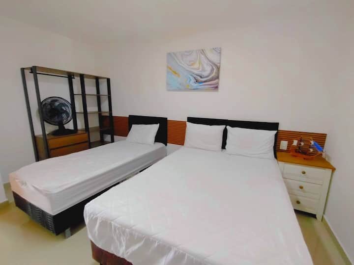 1号卧室配有一张双人床和一张单人床、便携式风扇、遮光窗帘和存放衣服的地方。