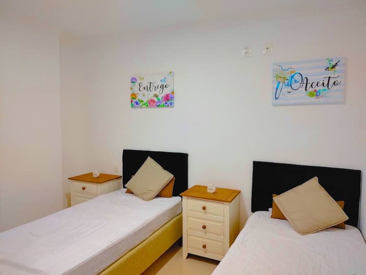 2号卧室配备两张单人床、便携式风扇、遮光窗帘和存放衣服的地方。