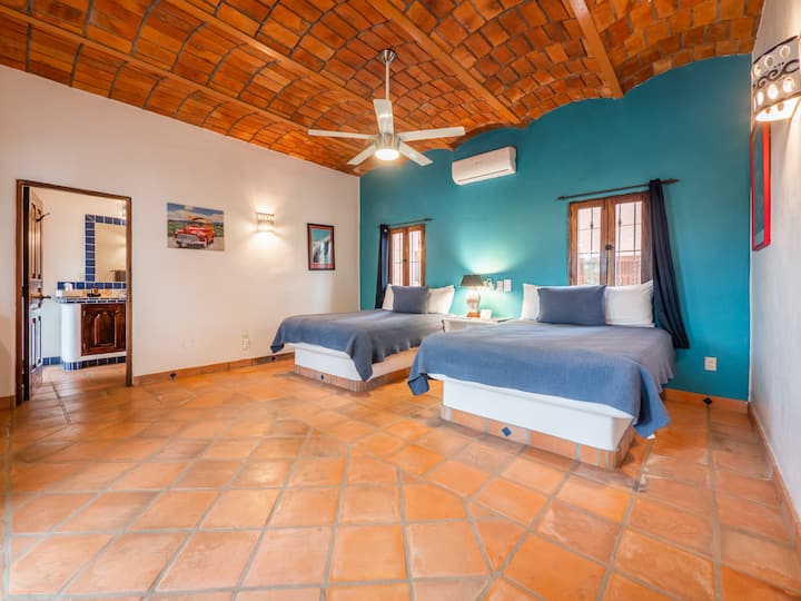 غرفة النوم 1 في الطابق الأول من البيت الرئيسي.  يحتوي على سريرين كبيرين وإمكانية الوصول إلى الحمام المشترك مع منطقة حمام السباحة (حمام كامل 1).