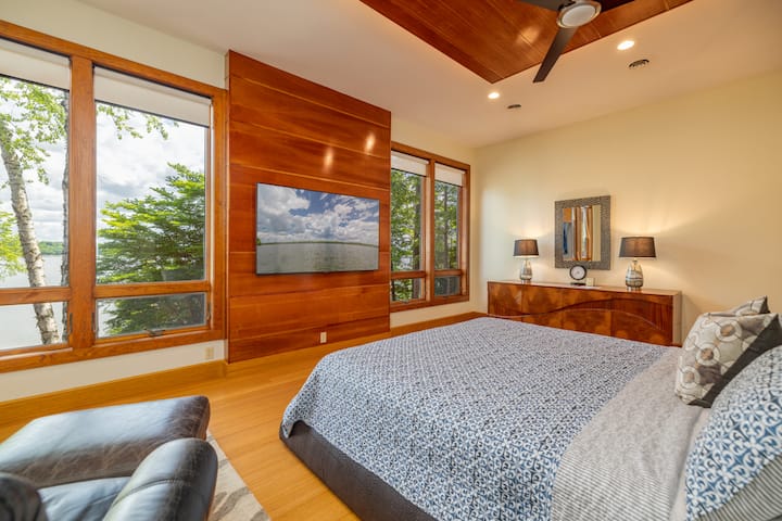 Primary bedroom on main floor with king bed, large smart tv, seating, views of the lake and ensuite bathroom