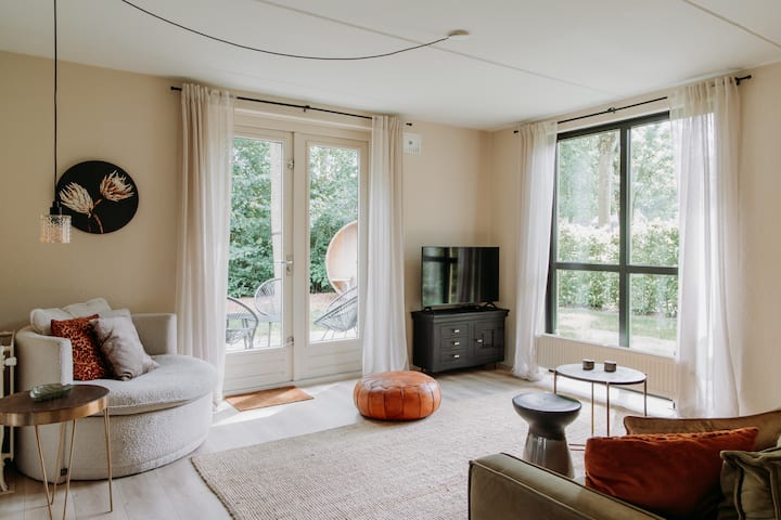 ห้องนั่งเล่นที่อบอุ่นพร้อมประตูฝรั่งเศสที่เชื่อมต่อกับสวน