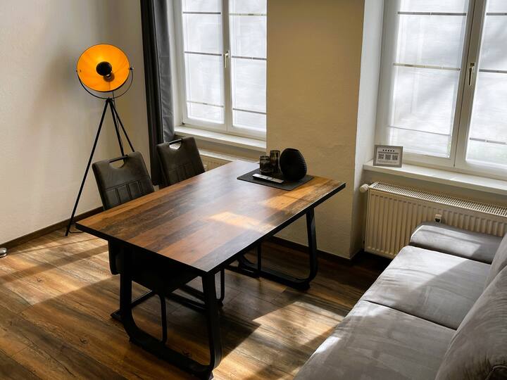 客厅明亮，配有餐桌、拉出式沙发床和现代平板电视。