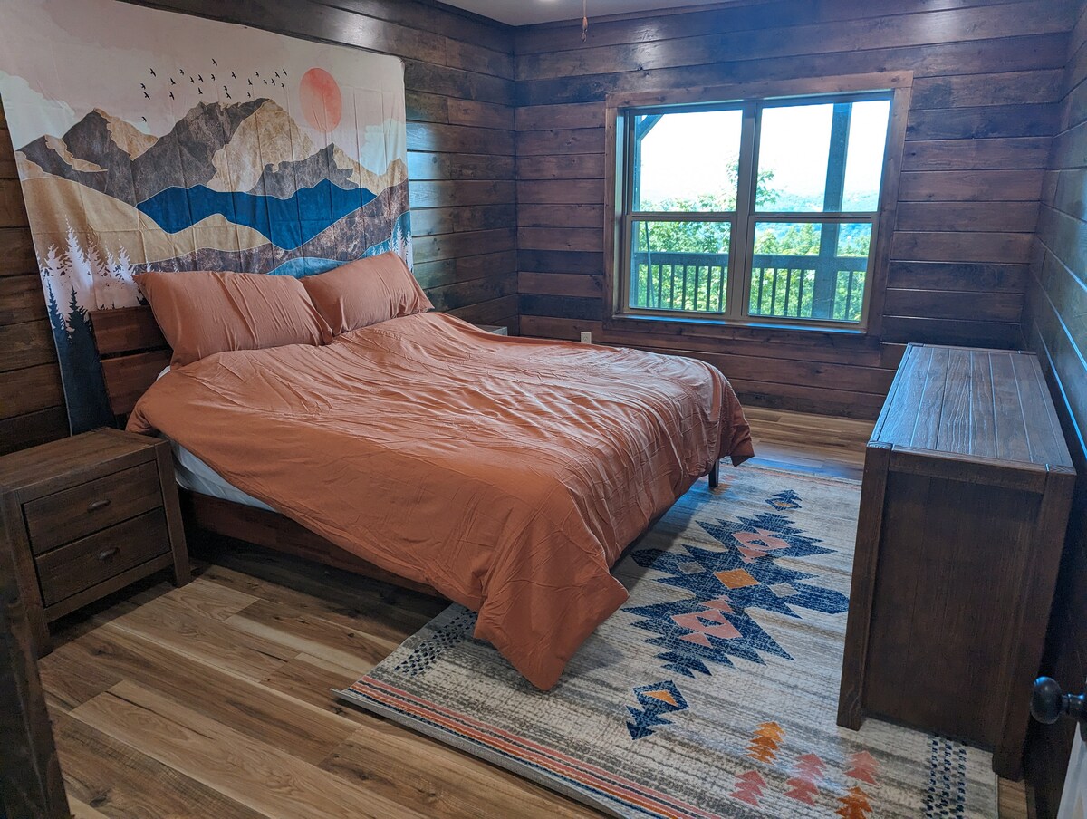 ห้องพักชั้นล่างพร้อมเตียงคิงไซส์และเน้นไม้ให้ความรู้สึกเหมือนอยู่ในเคบิน