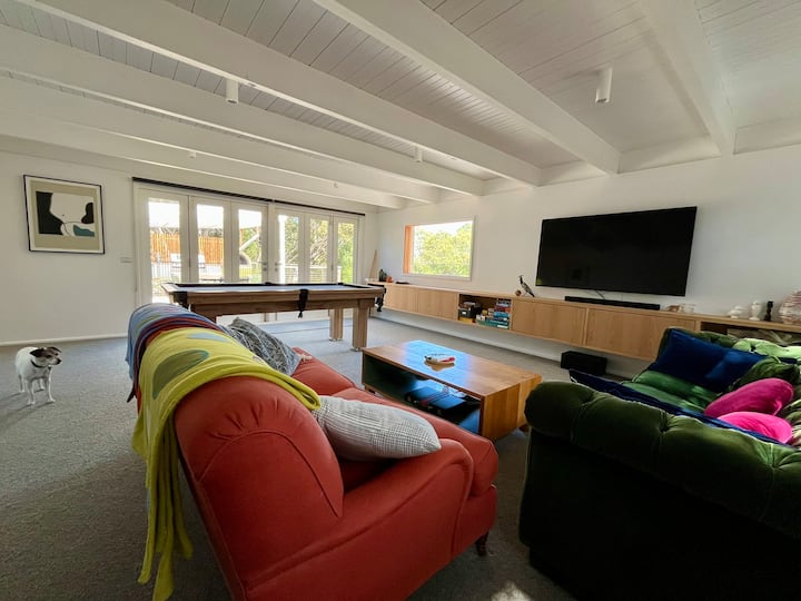 Ambienti i dytë i madh i ndenjjes me pamje nga veranda e pasme dhe zona e ngrënies/barbekju në natyrë. Ka tavolinë pishine, televizor të madh dhe vend për të vendosur dyshekë shtesë nëse qëndrojnë vizitorë të tjerë. Roo,m ka sistem ngrohje/ftohje të ndarë.
