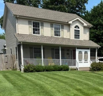 The exterior of the house features a two-story design with light beige siding and green shutters. A welcoming front porch is lined with colorful adirondack chairs, and a manicured lawn with neat stripes enhances the home’s curb appeal.
