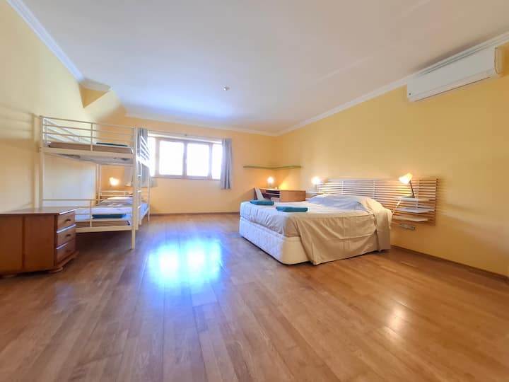Bedroom 4 on the ground floor with a double bed, twin bunk beds, AC, wardrobe, bedside tables, drawers, desk and chair