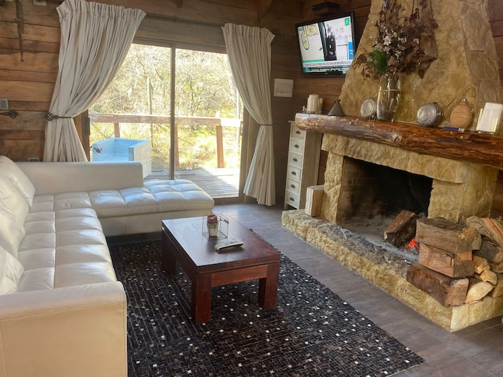 Dhoma kryesore e ndenjjes, e pajisur me TV satelitor, oxhak, pamje, karrige, divan, pyll, banjë dhe e integruar me dhomën e ngrënies dhe kuzhinën