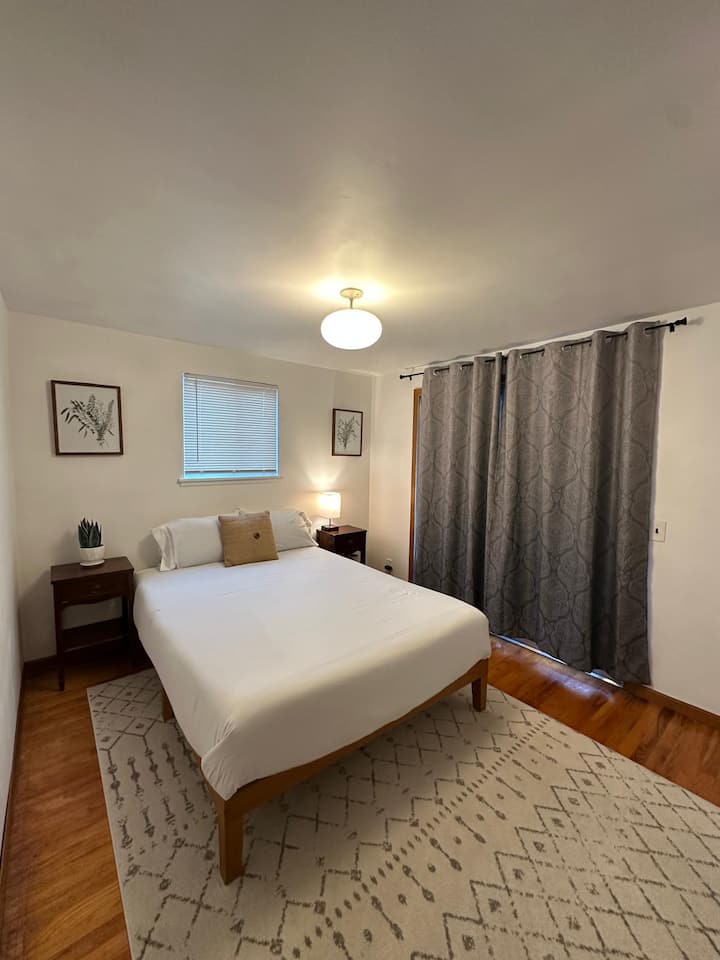 Დაისვენეთ ამ მშვიდ, მზით განათებულ საძინებელში, რომელშიც დგას კომფორტული ორადგილიანი საწოლი, ხის თბილი იატაკი და უშუქო ფარდები, რომ მშვიდი ძილი ან დილა გათენდეს.