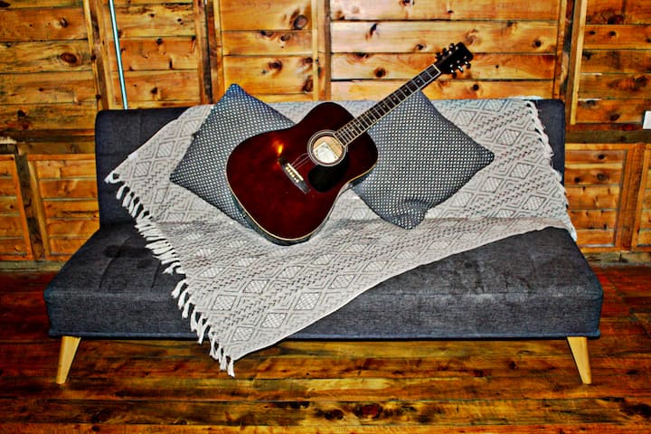 Canapé-lit pour 2 personnes, TV en haut, ventilateur sur pied, guitare disponible et poids si vous voulez vous entraîner. Un espace confortable pour se reposer ou profiter.