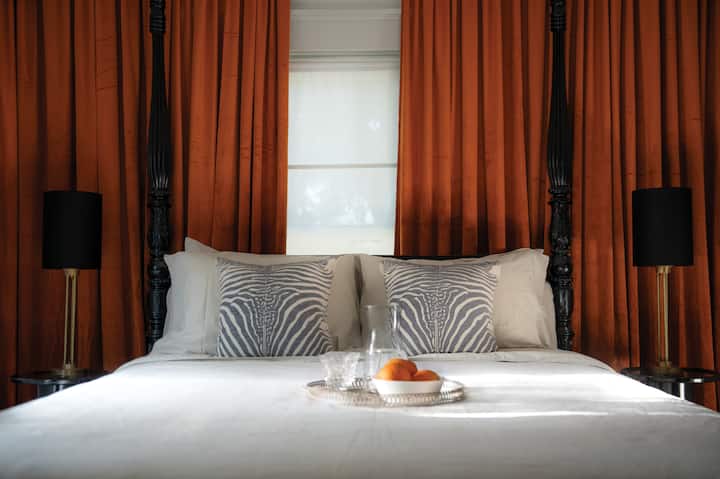 توفر غرفة النوم الرئيسية مدخلًا خاصًا مباشرًا إلى الحمام الرئيسي، وستارة مخملية برتقالية برتقالية مريحة، وتلفزيون ذكي خاص بك، وصالة صغيرة على كرسي بذراعين للاسترخاء في الغرفة. مساحة واسعة لخزانة الملابس في خزانة الملابس الخاصة بك