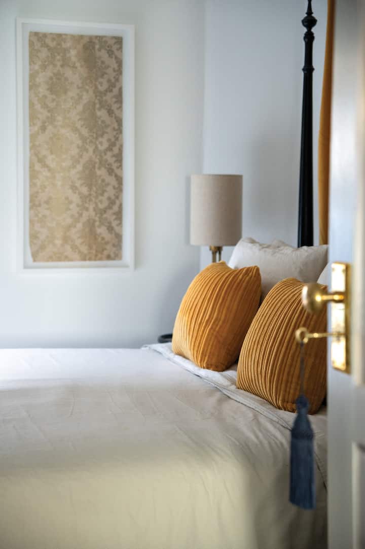 تتمتع غرفة النوم الذهبية بإمكانية الوصول المباشر إلى المساحات الاجتماعية للبيت - حيث يفتح الباب باتجاه منطقة تناول الطعام. يوفر المسكن كرسيًا صغيرًا بذراعين وتلفزيونًا ذكيًا خاصًا بك ولوح رأس ستارة مخملية صفراء جميلة ومساحة واسعة لخزانة الملابس. 