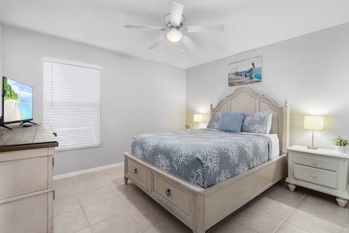 Bedroom 4 offers a queen sized bed, smart TV, mirror, closet and armoire for clothing storage. Big, bright windows offer lots of natural light and a view of pool and lake. 