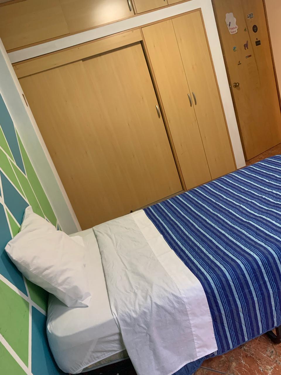 غرفة واسعة بسرير فردي وملاءات بيضاء وخزانة كاملة.