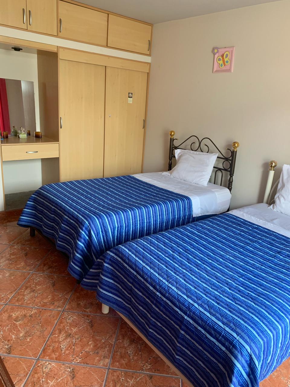 غرفة واسعة، بسريرين ونصف وملاءات بيضاء وخزانة كاملة وتحتوي أيضًا على مروحة. 