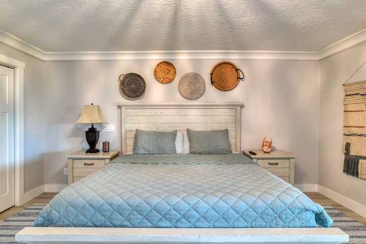 Our master bedroom features a plush king-size bed and doors leading out to the sunroom, offering a perfect space for relaxation.