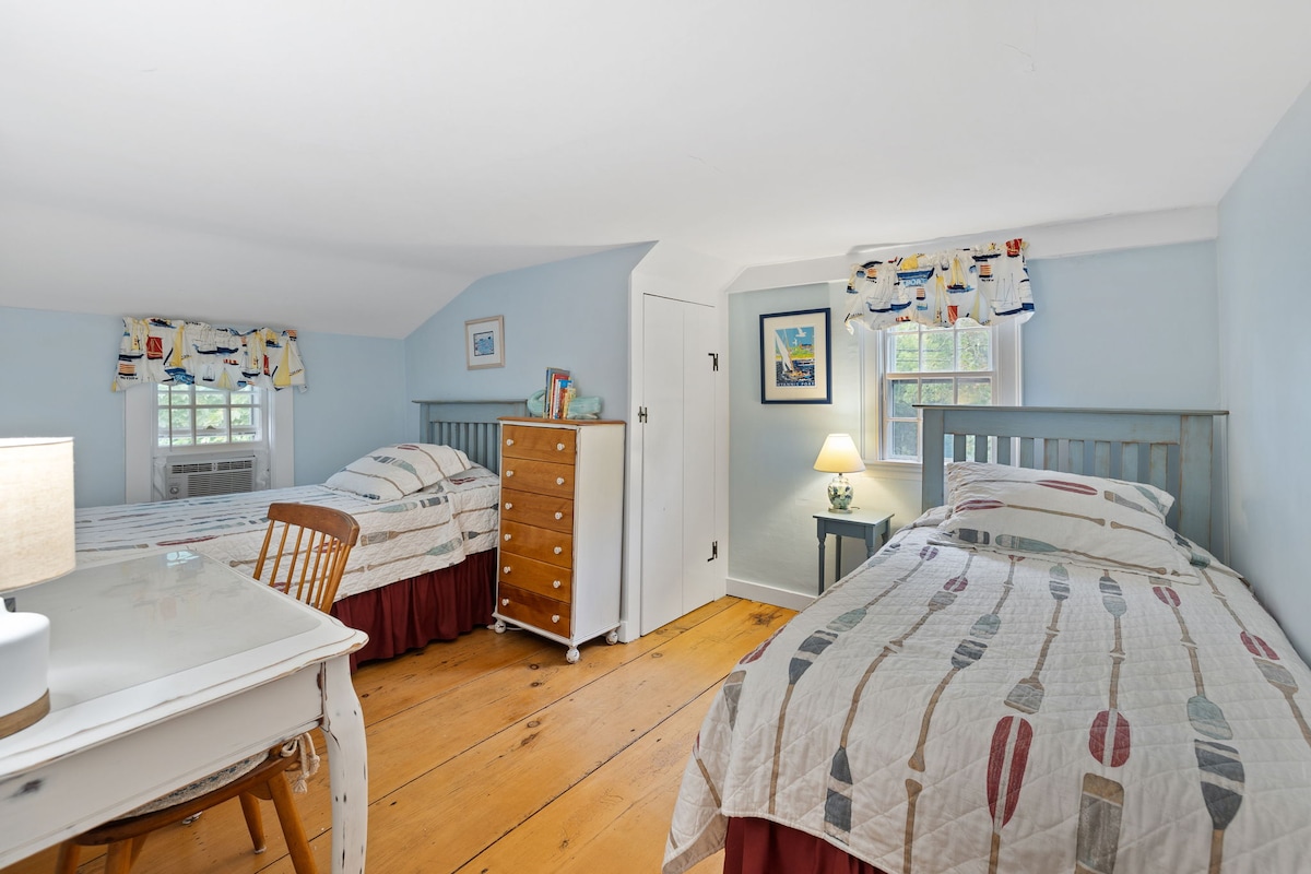 Detta sovrum med ~6' tak har två enkelsängar och ett skrivbord.