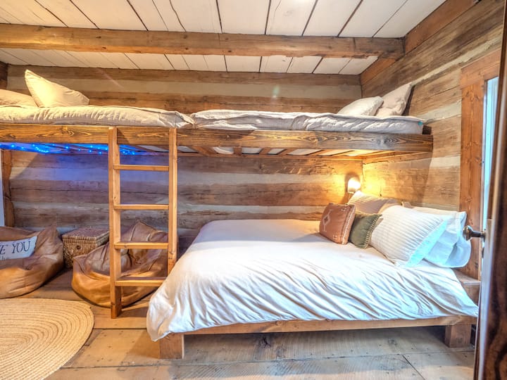The cozy loft is perfect for kids or extra guests, with hand-built bunks, soft throws, and a gentle mountain glow.