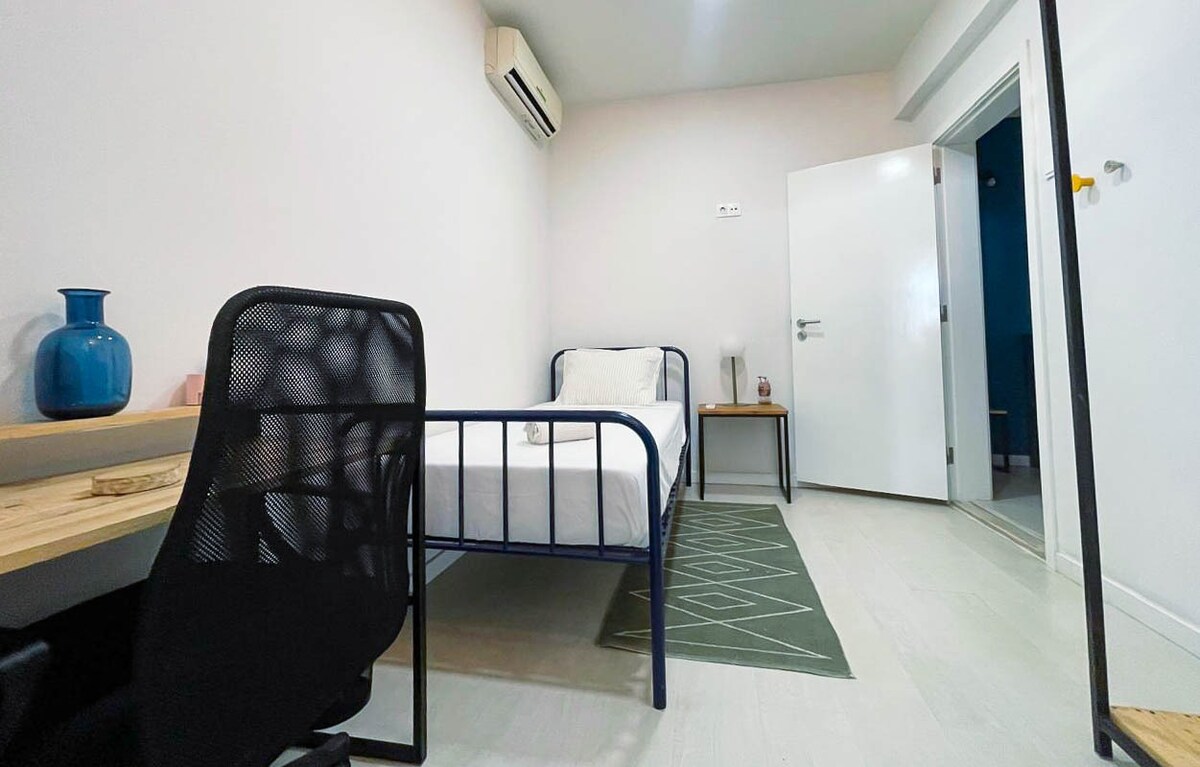 配有空调和床头柜的简约单人卧室。