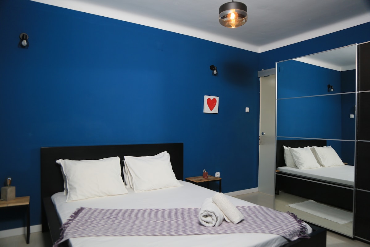 时尚的蓝色套房，配有舒适的床、镜面衣柜和独立卫生间