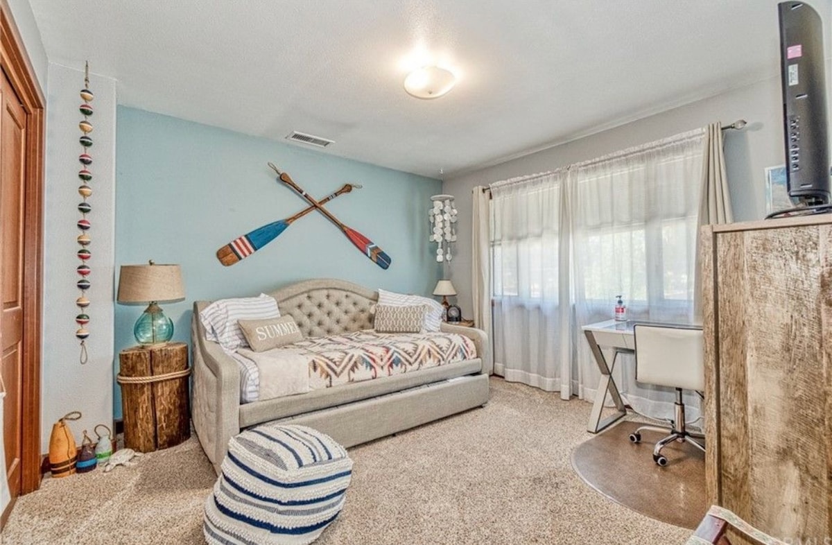 Спална соба на горниот кат со двоен кревет, биро за работа и стол.