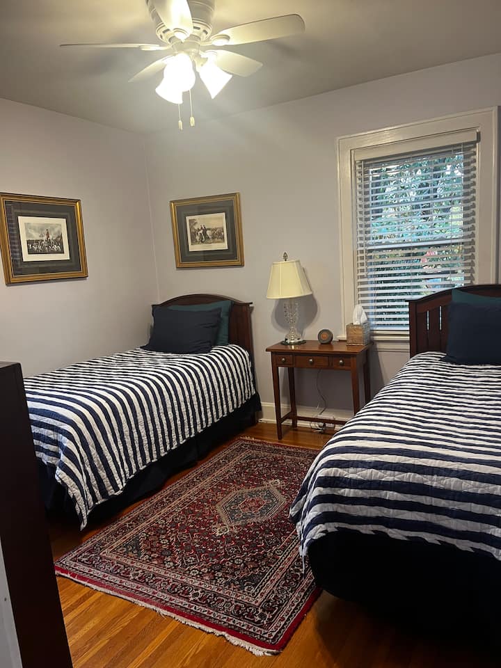 غرفة نوم في الطابق الأول بسريرين متماثلين، والحمام بجوار غرفة النوم. آلة النوم وصندوق المناديل في غرفة النوم. مروحة سقف مع أضواء.