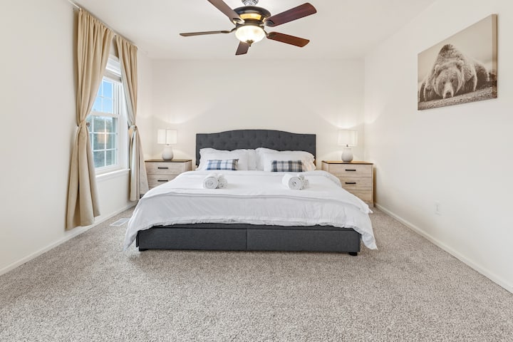 Détendez-vous dans la chambre principale spacieuse, avec un matelas king size en mousse à mémoire de forme pour un confort ultime. Les grandes fenêtres offrent une vue paisible sur la cour avant, tandis que les lampes de table de nuit et un ventilateur de plafond avec lumière créent un espace confortable et reposant.