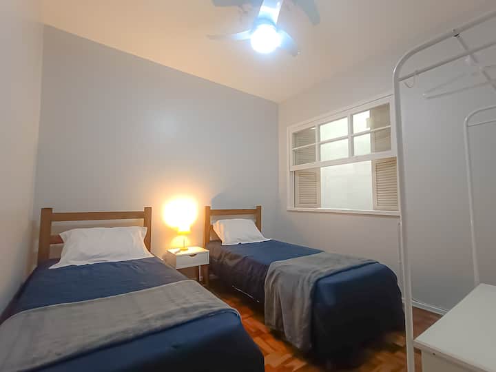 ორი ერთადგილიანი საწოლი, ჭერის ვენტილატორი და ღია კარადა