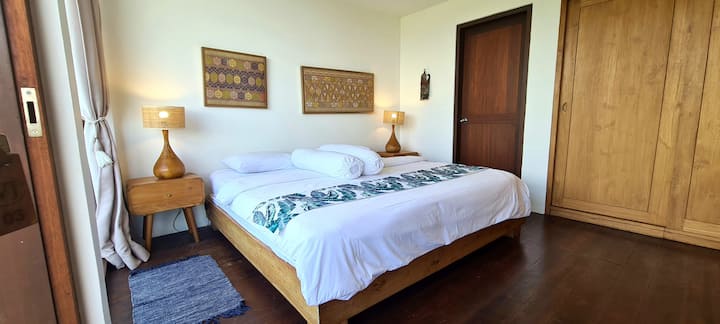 The Second Bedroom, situated on the main floor, features stunning, unobstructed views of the surrounding mountains and lake. It includes a king-sized bed, ample storage with cupboards, a writing desk, and a private adjoining bathroom for comfort.