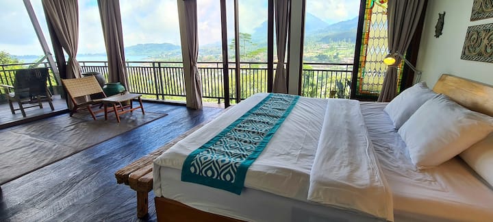The First Master Bedroom, on the top floor, boasts breathtaking, unobstructed mountain and lake views. It features a king-sized bed, a wraparound balcony, ample storage, a writing desk, and a private bathroom with a bathtub.