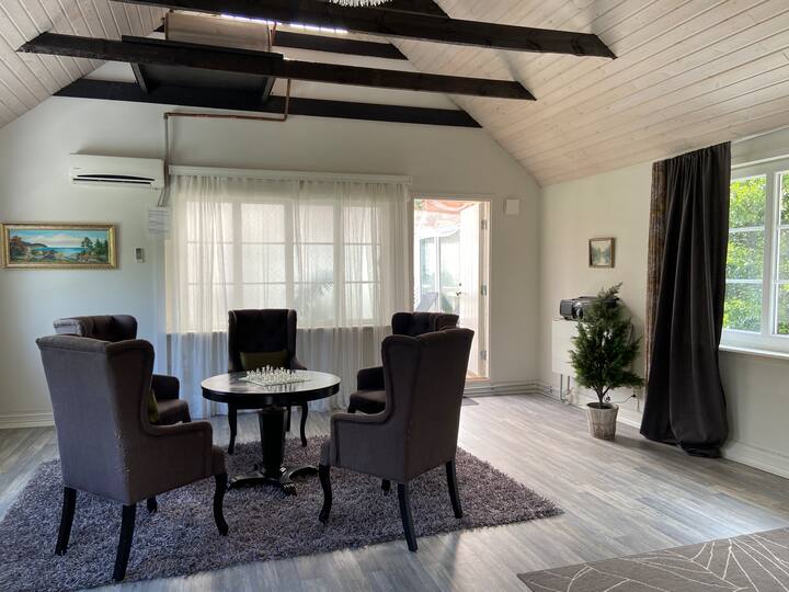 Allrum med 5 bekväma fåtöljer och dörr ut till lilla terrazen. Högt till tak och synliga takbjälkar. Ljust och rymligt.