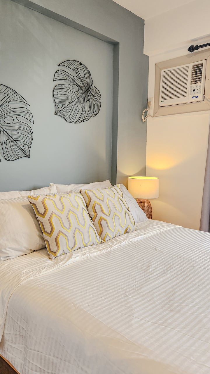 Cama tamaño queen con mesa auxiliar y lámpara