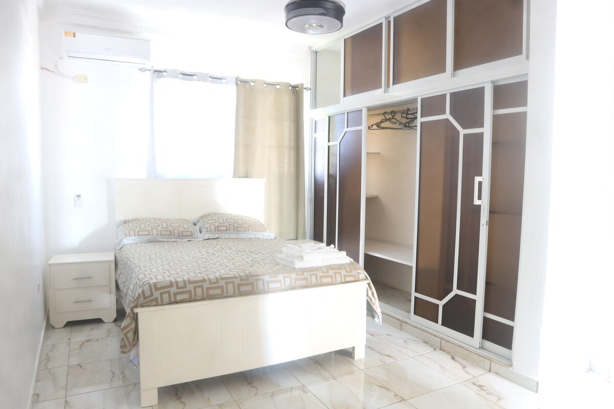 Hlavná izba ponúka všetko, čo potrebujete na dokonalý odpočinok: klimatizáciu, stropný ventilátor, televízor a vlastnú kúpeľňu pre väčšie pohodlie a relaxáciu.