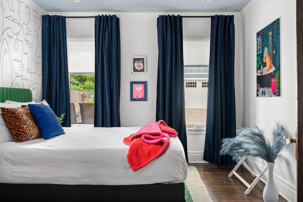 Ova strana spavaće sobe odlikuje se živopisnim bojama, elegantnim ukrasima i velikim prozorima s tamnoplavim zavjesama koje ispunjavaju prostor prirodnim svjetlom.