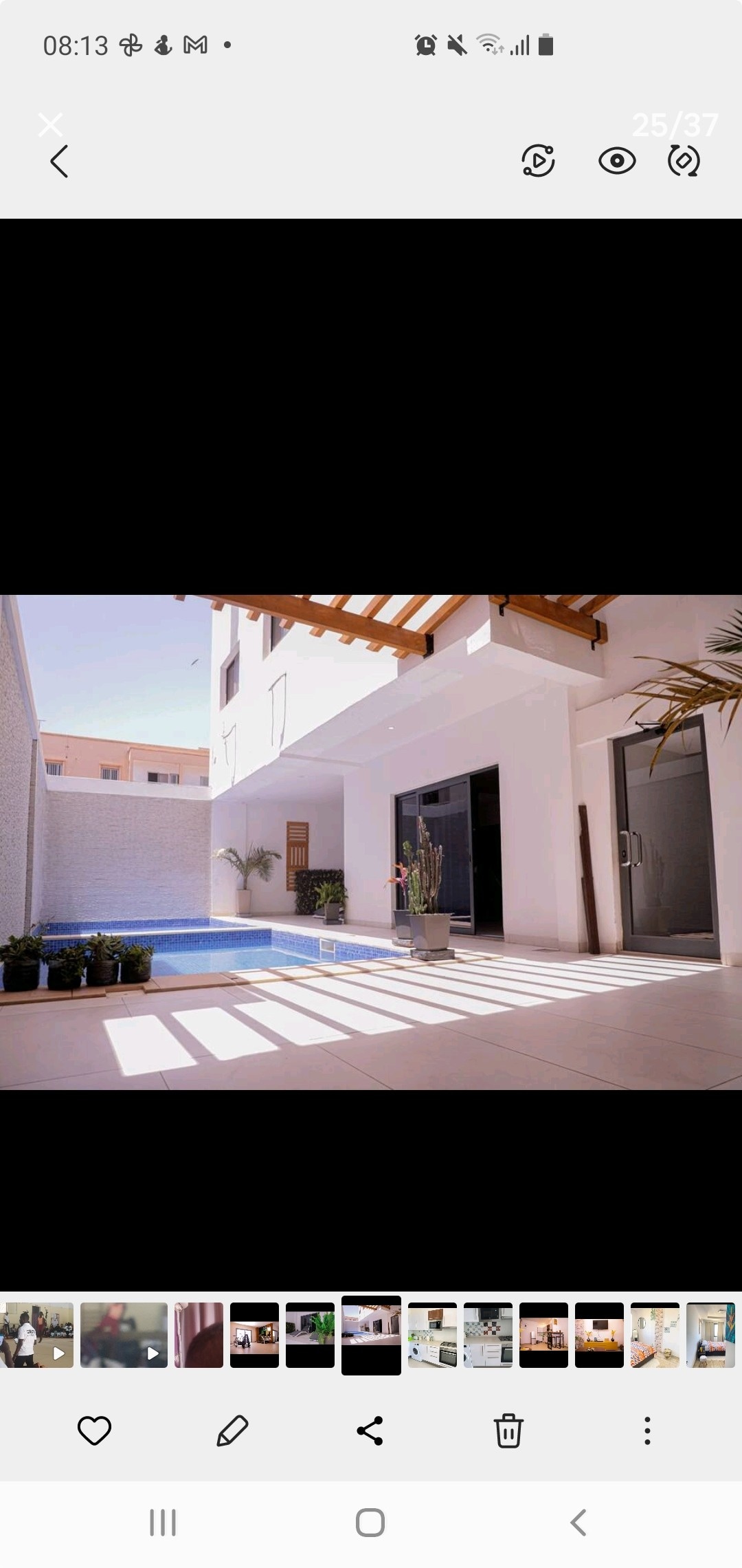 A modern outdoor area features a small pool alongside sleek tiled flooring. Natural light filters through wooden beams, creating striped shadows on the surface. Potted plants add greenery, enhancing the serene ambiance. Large glass doors provide access to the interior, promoting an open feel.