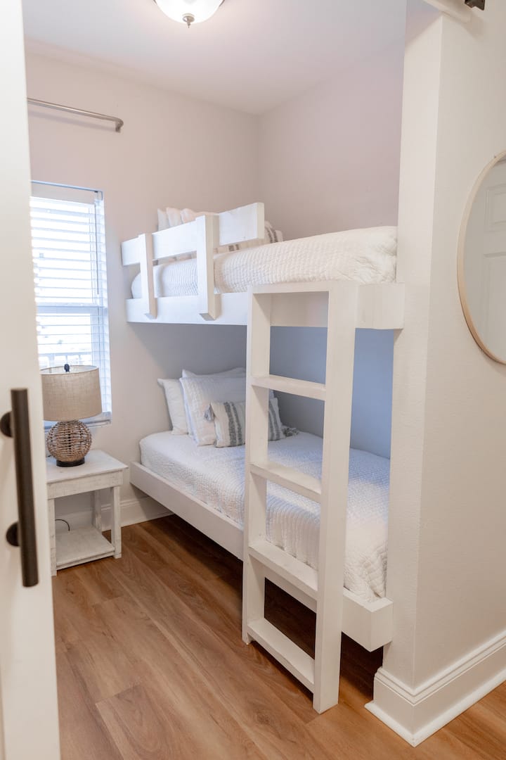 Habitación con litera con puerta de granero para privacidad y cortinas oscuras.