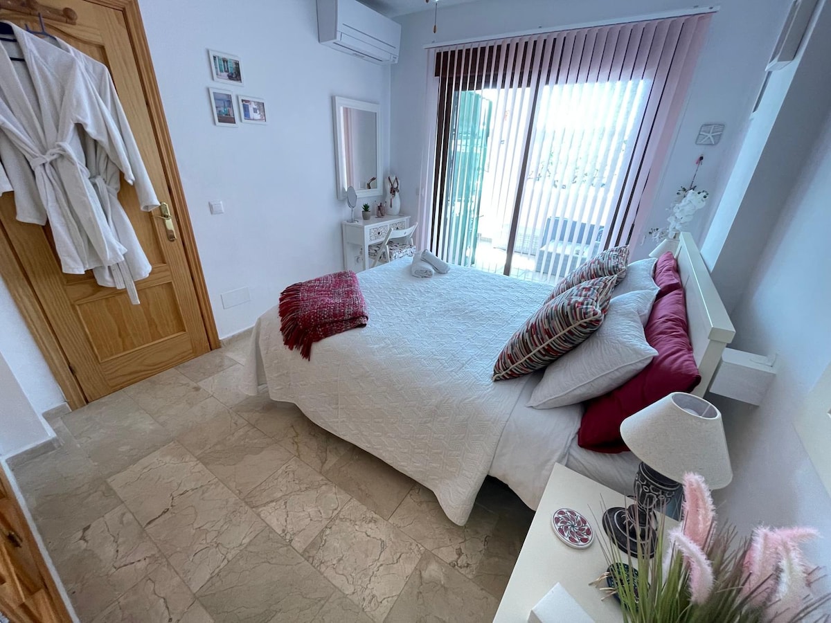 Dormitorio principal con cama tamaño king, puertas a la terraza de abajo con vistas al jardín