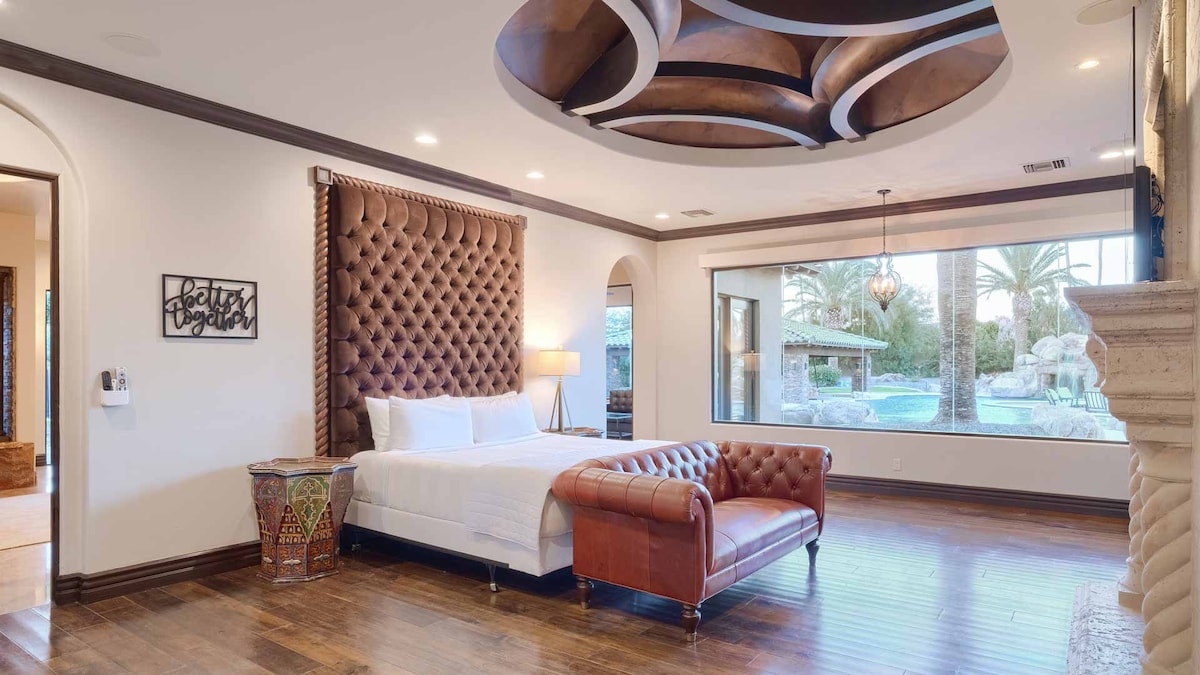 Elegantna spavaća soba s tapeciranim uzglavljem, kožnom garniturom, pogledom na bazen i vlastitom kupaonicom. 