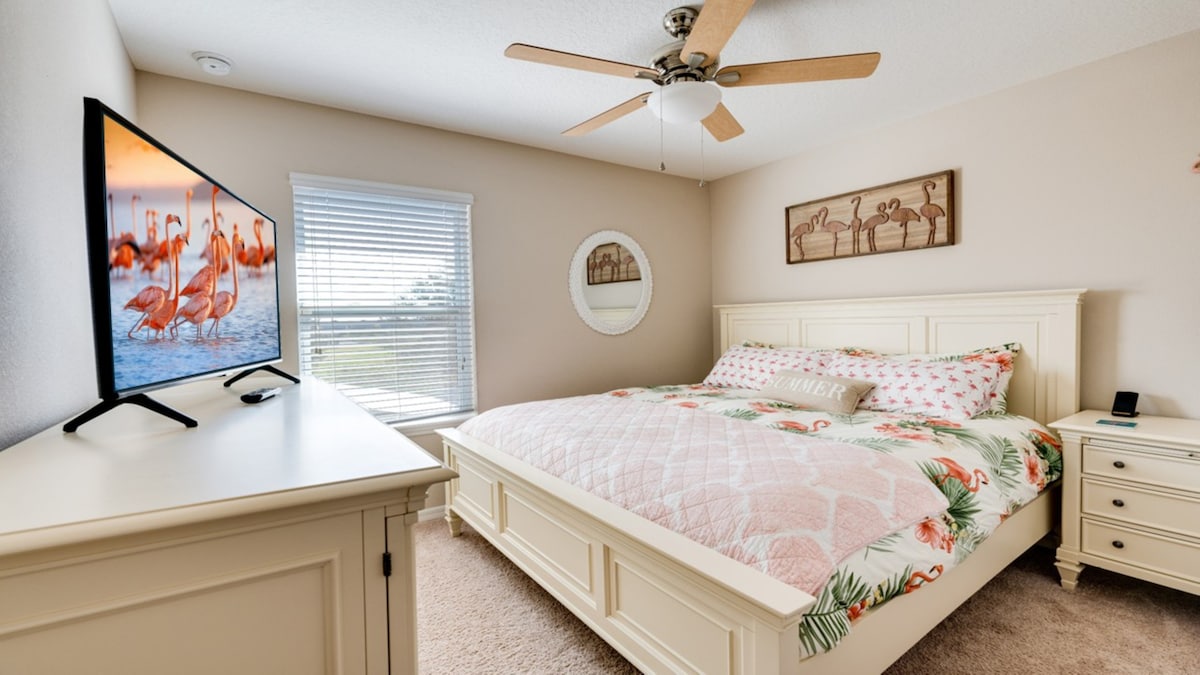 Chumba cha kulala cha ghorofa ya pili *Flamingo*: kina kitanda cha ukubwa wa King, runinga mahiri, kabati, kabati la nguo, stendi ya karibu, chaja ya simu na bafu kamili karibu na mlango.
