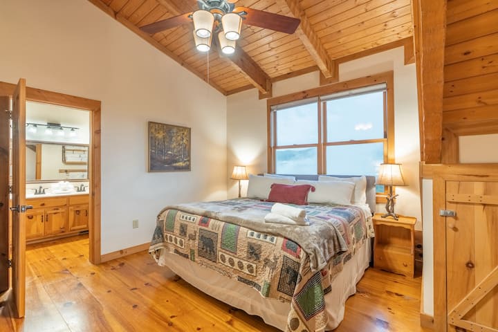 Second-floor master bedroom with king bed, dedicated workspace, & stunning million-dollar mountain views. Walk-in closet w/ lighting, full-length mirror, smart TV, ceiling fan, and convenient ensuite with tub/shower accessible from bedroom and hall.
