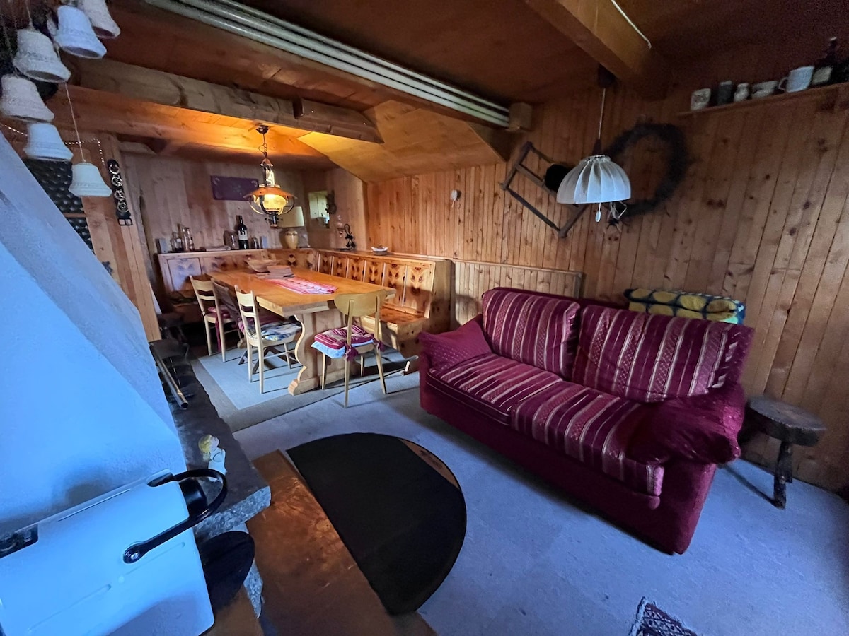 Sala con mesa y sillas de madera, chimenea y sofá cama.