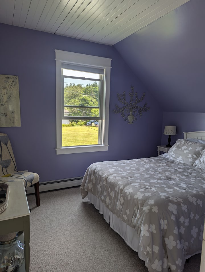 Bedroom equipped with a queen bed, closet space, dressing char, and small TV